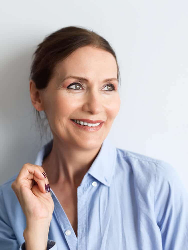 Mature woman smiling against a gray wall